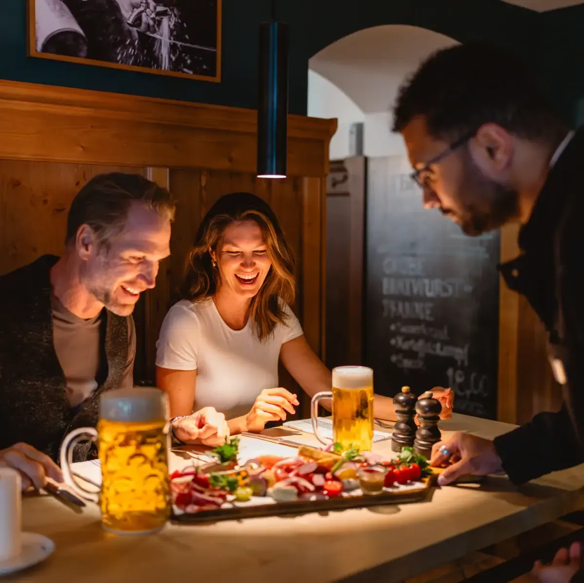 Freunde genießen gemeinsam eine Brotzeit mit frisch gezapftem Bier im Tegernseer Wirtshaus in Binz